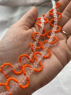 an orange and white beaded necklace being held in someone's hand with it