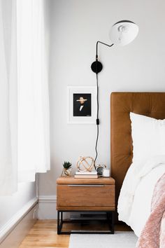 a bed room with a neatly made bed and a lamp on the nightstand next to it