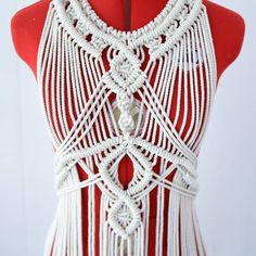 a red and white dress on a mannequin's torso with an intricate design