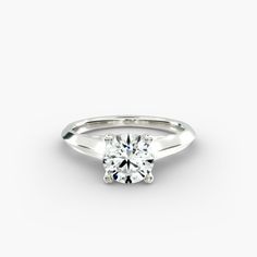 a white gold engagement ring with a round brilliant cut diamond in the center, on a plain surface