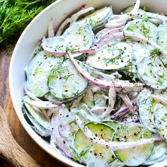 a white bowl filled with cucumbers and onions