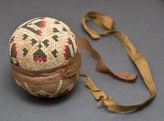 an old ball with a ribbon tied around it on a gray surface next to a lanyard