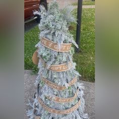 a christmas tree made out of cardboard wrapped in ribbon with words written on the top