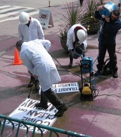 three people in white lab coats are working on some signs and equipment at an intersection