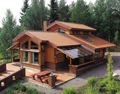 a wooden house sitting on top of a lush green hillside next to a wooded area