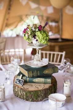 a table topped with books and flowers on top of each other next to wine glasses