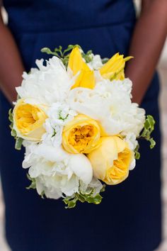 a bride holding a bouquet of yellow and white flowers