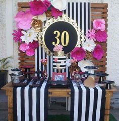 the table is decorated with pink flowers and black and white striped cloths on it