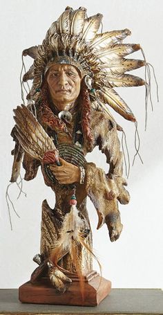 a statue of a native american man with feathers on it's head and hands