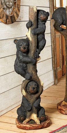 three bears are climbing up the side of a wooden pole on wood planks in front of a wall