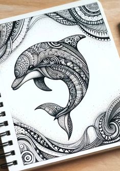 a spiral notebook with a drawing of a dolphin on the cover and an ink pen next to it