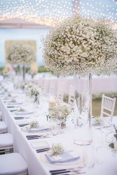 the tables are set with white flowers and place settings