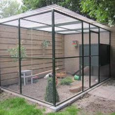 a large caged in area with some plants and animals inside it on the side of a building