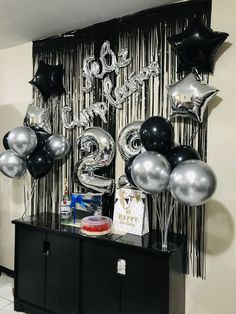 balloons and streamers are on display in front of a black cabinet with the number twenty five