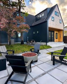 an outdoor patio with chairs and fire pit in front of a house on a sunny day