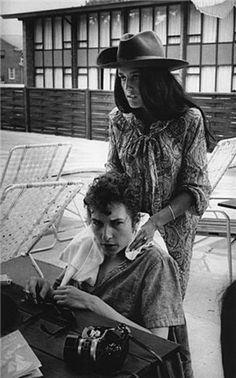 an old black and white photo of a woman sitting next to a young man with a camera