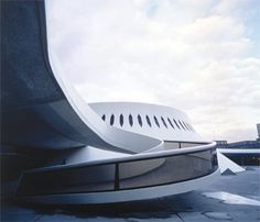 an airplane sitting on top of a tarmac next to a tall building with a sky in the background