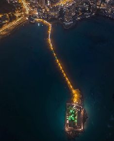 an aerial view of a city at night with lights on the water and buildings in the background