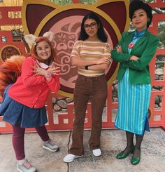 three women standing next to each other in front of a red sign with an animal on it