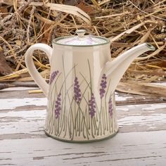 a ceramic tea pot with lavender flowers painted on it