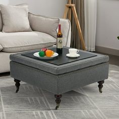 a living room with a couch, coffee table and bottle of wine on the ottoman