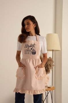 a woman standing in front of a lamp wearing an apron with the words nails by brad on it