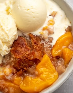 two scoops of ice cream are in a bowl with peaches and cobbles