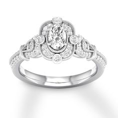 a white gold ring with an oval cut diamond surrounded by smaller round diamonds on the band