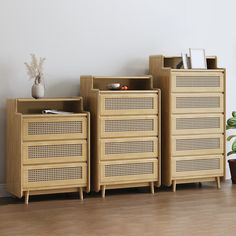 three wooden drawers sitting on top of a hard wood floor next to a potted plant