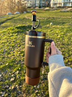 a person holding a coffee cup in their hand with the lid up and an espresso machine attached to it