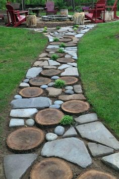 a stone path made out of logs in the middle of a grassy area with chairs around it