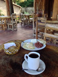 a cup of coffee and some food on a table in front of a wooden structure