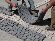 two men are working on some kind of brick walkway that is being built into the ground