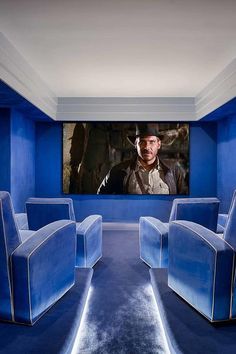 a movie room with blue chairs and a large screen