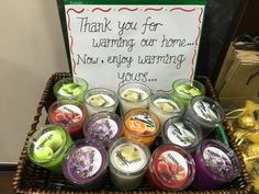 a basket filled with lots of different types of candles next to a sign that says thank you for warming our home now, enjoy warming yours