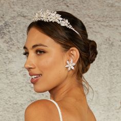 a woman wearing a bridal headpiece with flowers on it's side, smiling at the camera