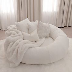 a large white round bed sitting on top of a carpeted floor next to curtains