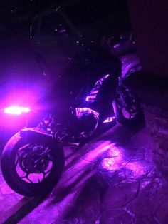 a motorcycle parked in the dark with purple lights on it's front tire rims