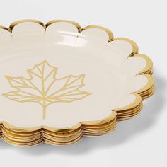 a stack of white and gold plates with a leaf on the front one is empty