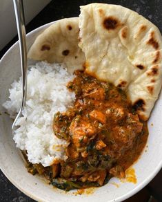 a white bowl filled with rice, meat and veggies next to pita bread