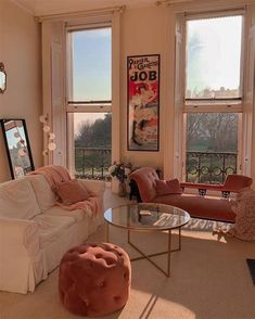 a living room filled with lots of furniture next to two large windows and a painting on the wall