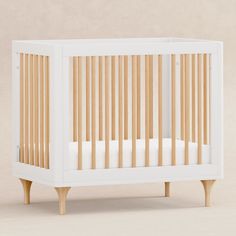 a white crib with wooden slats on the bottom and sides, against a beige background