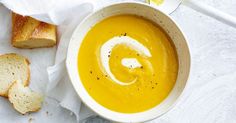 a bowl of soup and some bread on a white cloth with a spoon in it