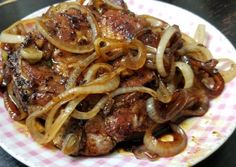 a plate full of onions and meat on top of a checkered table cloth with a fork