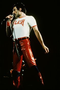 a man in white shirt and red pants holding a microphone