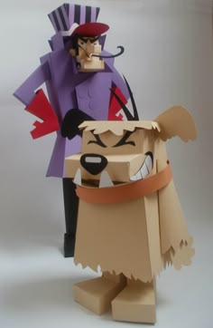 two paper toys are standing next to each other on a white surface, one is wearing a purple hat and the other has a brown dog