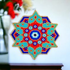 a cross - stitch pattern is displayed on the wall next to a vase with flowers