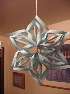 a paper snowflake hanging from a ceiling in a room with pictures on the wall