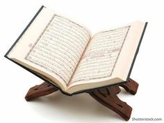 an open book sitting on top of a wooden stand with arabic writing in the middle