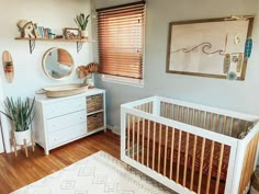 a baby's room with a crib, dresser and mirror on the wall